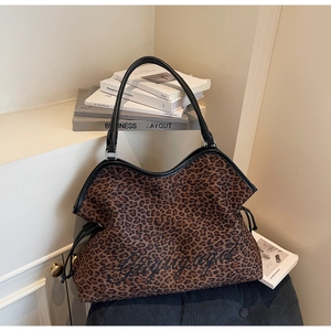 Detail of leopard print tote bag with black handles and elegant cursive embroidery