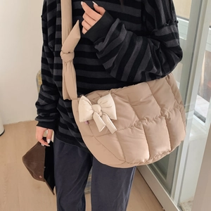 Détail d'un sac à bandoulière matelassé beige avec nœud décoratif et large bandoulière