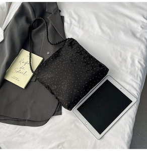 Detail of black polka dot crossbody bag with a thick woven strap on a grey blazer