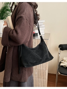 Close-up of black leather hobo bag with white contrast stitching and slim shoulder strap