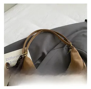 Detail of adjustable strap and metal hardware on a brown faux leather shoulder bag