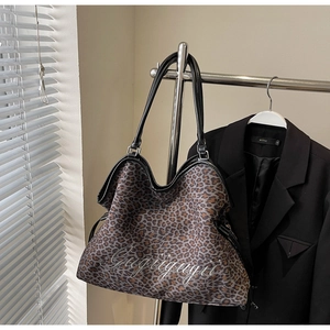 Detail of leopard print tote bag with white embroidery and black leather straps
