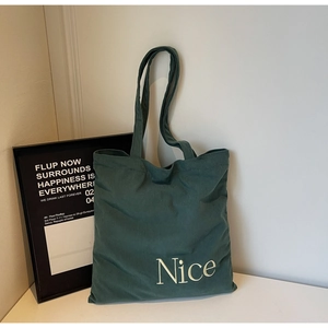 Detailed texture of dark green corduroy tote bag with white Nice letter embroidery