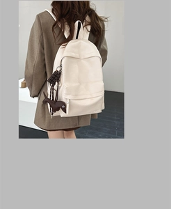Détail d'un sac à dos beige en similicuir avec charme de chien et logo embossé