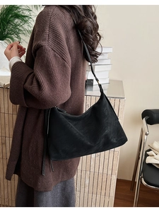 Detail of black hobo bag featuring contrast white stitching on leather texture surface