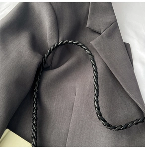 Detail of dark grey twill suit fabric texture paired with a black woven leather bag strap