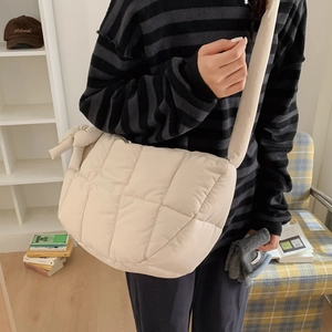Détail du sac bandoulière matelassé beige avec nœud sur la sangle et texture douce