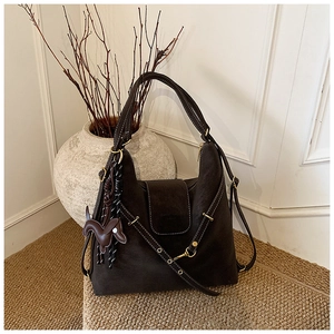 Detailed macro view of dark brown suede bag with contrast stitching and horse charm