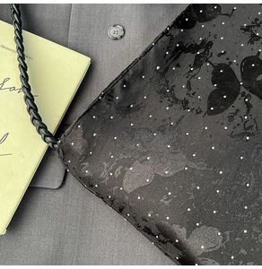 Detail of black polka dot bag with butterfly print and woven leather shoulder strap