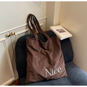 Close-up of brown corduroy tote bag showing soft ribbed texture and Nice embroidery