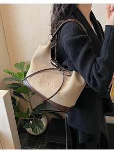 Detail of beige suede shoulder bag with brown leather bow and embossed lettering