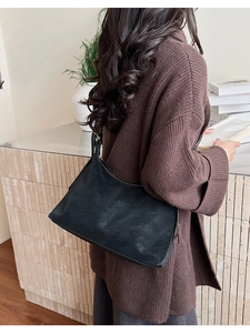Detailed view of a black vintage underarm bag worn with a winter sweater