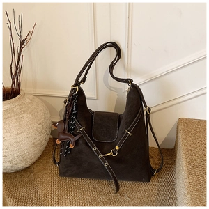 Close-up of dark brown suede tote bag featuring white contrast stitching and a dog charm
