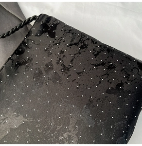 Close-up of black satin fabric with butterfly prints and sparkling rhinestone details