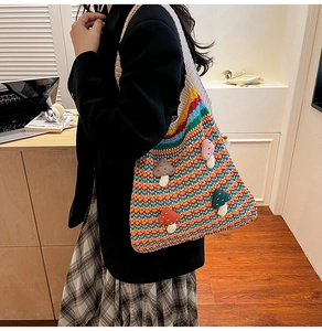 Close-up of rainbow crochet shoulder bag with colorful mushroom patches and knit texture