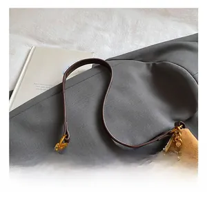 Detail of brown suede bucket bag with leather handle and gold chain decoration