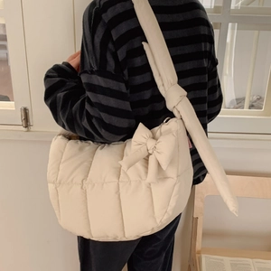 Grand sac à bandoulière matelassé crème avec détail de nœud porté par un mannequin