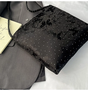 Detailed close-up of a black satin butterfly-patterned shoulder bag with dotted fabric texture