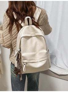 Vue détaillée du sac à dos en similicuir crème avec texture souple et breloque poney