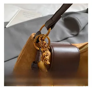 Detailed close-up of brown suede bag featuring gold metal hardware and a decorative tassel