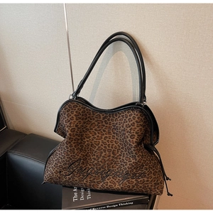 Close-up of leopard print tote bag featuring black cursive embroidery and leather straps