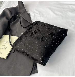 Detail of black polka dot bag with butterfly pattern and braided shoulder strap