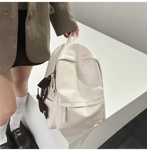 Détail d'un sac à dos minimaliste en cuir crème avec pendentif chocolat et lapin