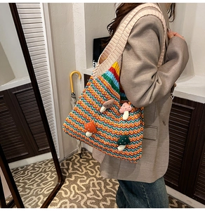 Detail of a colorful striped knit tote bag with 3D mushroom accents on a model