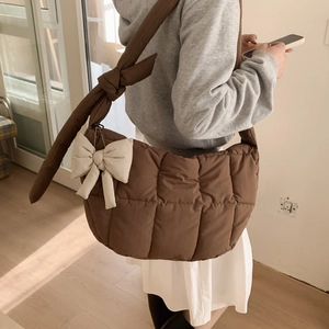 Gros plan du sac à bandoulière matelassé marron avec nœud blanc et bandoulière nouée