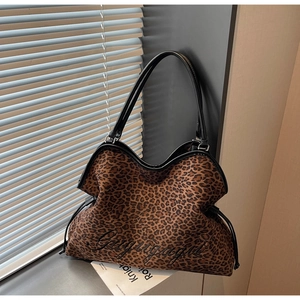 Detail shot of leopard print tote bag featuring black cursive embroidery and drawstring side