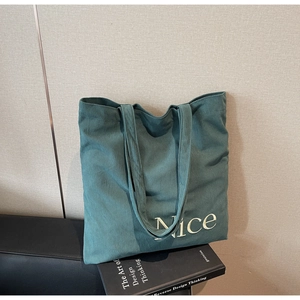 Close-up of the textured green corduroy fabric and white Nice embroidery on the tote bag
