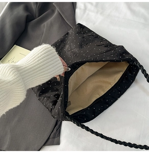 Close-up of black floral fabric underarm bag with white dots and woven handle detail