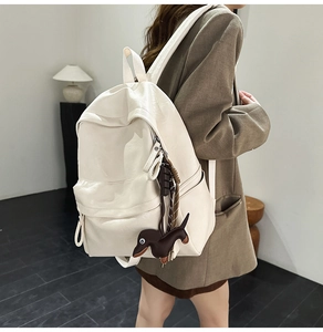 Détail du sac à dos en similicuir souple blanc crème avec un charmant pendentif de chien