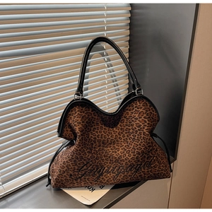 Close-up of leopard print tote bag with black leather trim and cursive embroidery detail