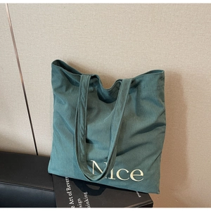 Detailed view of dark green corduroy fabric and white Nice embroidery on large tote bag