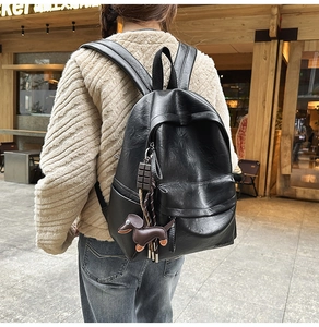 Détail d'un sac à dos vintage en cuir noir avec breloque teckel et finition PU texturée