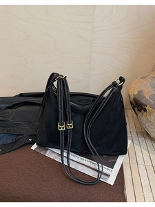 Detail of black tote bag featuring white contrast stitching and gold-toned metal hardware