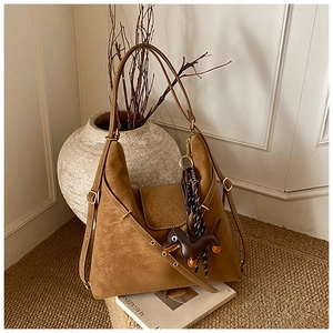 Close-up of brown suede shoulder bag with long strap and cute leather dachshund charm