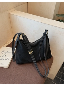 Detail of black pebbled leather tote with white contrast stitching and gold hardware