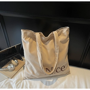 Detailed macro texture of beige corduroy tote bag with brown embroidered Nice lettering