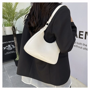 Detail view of cream white PU leather underarm bag worn with a black blazer