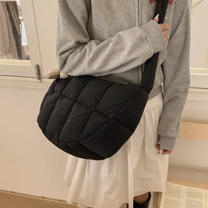 Vue détaillée du sac bandoulière matelassé noir avec texture douce et nœud beige
