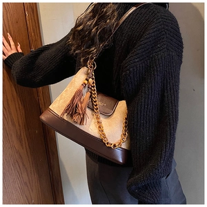 Détail du sac bandoulière matelassé en daim avec chaîne dorée et pompon en perles