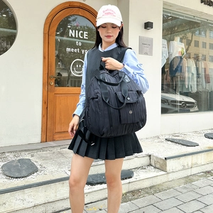 Close-up of black pleated texture nylon backpack featuring front pocket and trendy street style
