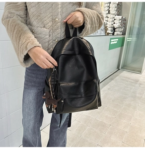 Détail d'un sac à dos vintage en cuir souple noir avec un charme de chiot et cordon tressé