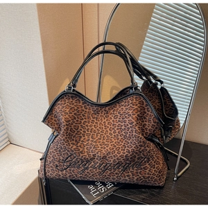 Detail of large leopard print tote bag featuring black script embroidery and sturdy handles