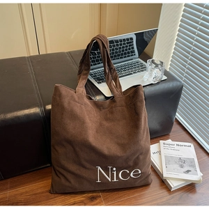 Close-up of brown corduroy tote bag with Nice embroidery on a leather bench