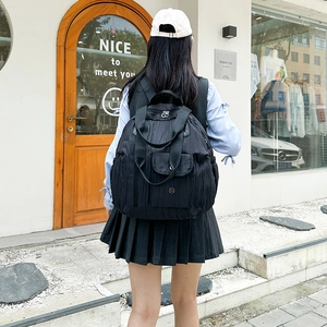 Outdoor shot showing a black nylon backpack with pleated texture on a female model