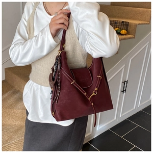 Detail of burgundy tote bag showing vintage matte leather texture and tassel charm