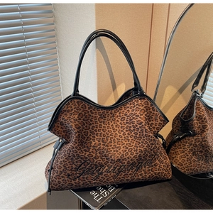 Detail of leopard print tote bag with black embroidery and leather straps in a room